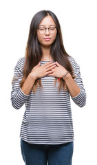 Young asian woman wearing glasses over isolated background smiling with hands on chest with closed eyes and grateful gesture on face. Health concept.