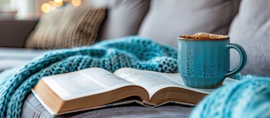 Fototapeta premium A blue coffee cup on the sofa beside an open book in a room with copy space image