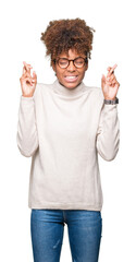 Beautiful young african american woman wearing glasses over isolated background smiling crossing fingers with hope and eyes closed. Luck and superstitious concept.