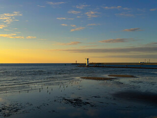 Sunset over the harbor. Lighthouse on the breakwater