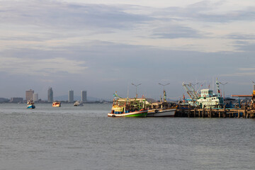 Fishing boat floating on the sea with city on background.