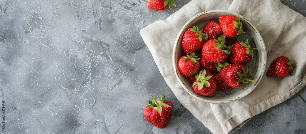 Aufkleber a vibrant red strawberry sits in a ceramic bowl on a linen napkin against a gray concrete background