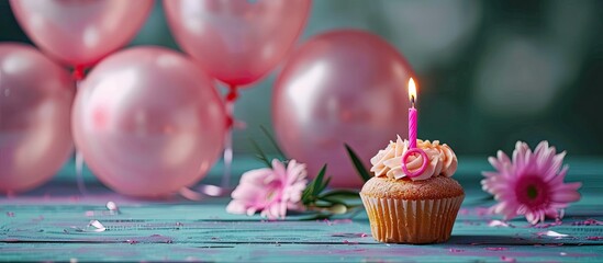 A woman s sixtieth birthday celebration decoration includes balloons a candle marked 60 pink flowers and a muffin with a lit candle above space for text or images available. with copy space image