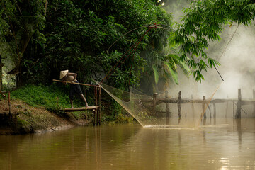 A farmer raises a net to capture fish in the river