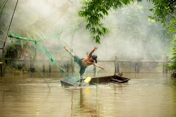 Two farmers on a boat in the river using a fishnet to catch fish © Wosunan