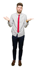 Young handsome business man clueless and confused expression with arms and hands raised. Doubt concept.