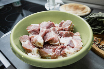 closeup of raw pork meat cut into pieces in the bowl. cooking process
