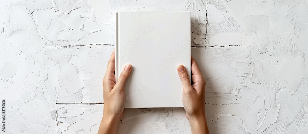 Leinwandbilder Two hands holding a white hardcover book with empty space for an image set against a white backdrop. with copy space image. Place for adding text or design