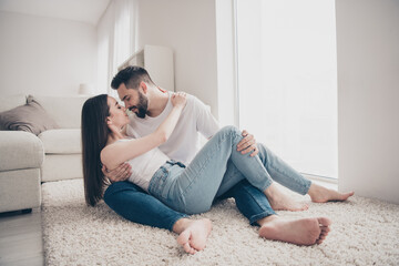 Full length photo of attractive cheerful married young couple spending free time lying floor hug move new apartment home interior indoors