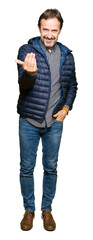 Fototapeta premium Middle age handsome man wearing winter coat Beckoning come here gesture with hand inviting happy and smiling