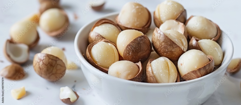 Poster macro view of whole unpeeled macadamia nuts with shelled kernels on a white background offering copy