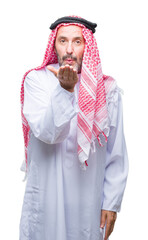 Senior arab man wearing keffiyeh over isolated background looking at the camera blowing a kiss with hand on air being lovely and sexy. Love expression.
