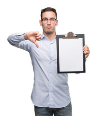 Handsome young business man showing a clipboard with angry face, negative sign showing dislike with thumbs down, rejection concept