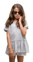 Naklejka premium Brunette hispanic girl wearing sunglasses touching mouth with hand with painful expression because of toothache or dental illness on teeth. Dentist concept.