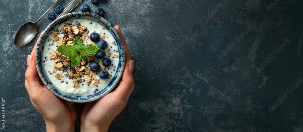 Poster Top view of a woman s hands holding a bowl with yogurt granola and blueberries with selective focus and empty space for text or other elements known as a copy space image