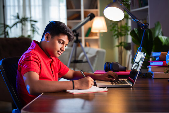 ndian Asian teenage student learning online with computer, headphones, and smartphone