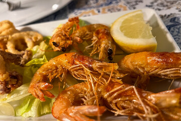 Grilled shrimp with lemon, garlic and white sauce on a plate at an Italian restaurant. Seafood