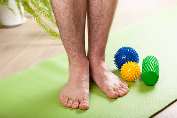 man doing flatfoot correction gymnastic exercise using massage roller at home