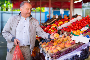 Man choosing peaches in market