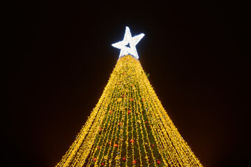 New Year christmas tree decorated Christmas balls with yellow flickering lights of garlands and...