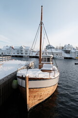 Wooden Boat Docked in Snowy Harbor