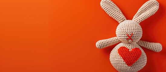 Heart shaped crochet design with a bunny doll on an orange backdrop perfect for love and Valentine s Day themes with copy space image