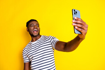 Photo of nice young man phone make selfie wear striped t-shirt isolated on bright yellow color background
