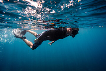 Caucasian Male snorkeler swimming in clear blue waters with mask, fins and snorkel tube