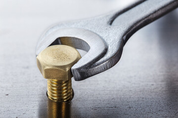 Wrench tightens bolt in steel billet. Spanner, bolt, screw and nuts.
