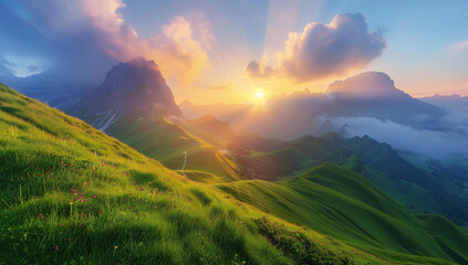 Fototapeta premium Beautiful summer landscape in the mountains, green grass on foreground and blue sky with sun rays over alpine valley at sunrise.