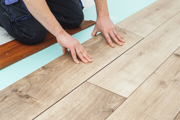 Worker installing new laminated wooden floor. Easy and quick installation of the flooring.