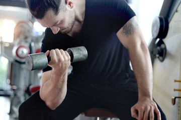 Strong young muscular man lifting dumbbell at gym. Handsome sport man doing weightlifting exercise at fitness. Athletic workout weight training, doing bodybuilding program for healthy and perfect body