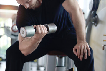 Strong young muscular man lifting dumbbell at gym. Sport man doing weightlifting exercise at fitness. Athletic workout weight training, doing bodybuilding program for healthy and perfect body