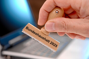 Ein Holzstempel ist beschriftet mit dem Aufdruck: Bundeshaushalt 2025