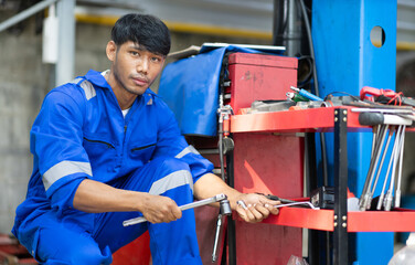 Auto mechanic standing holding wrench in garage.