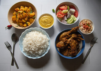 Indian lunch food items non veg main course rice, chicken, dal, vegetables and salad.