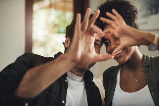 Heart hands, smile and portrait of couple in home for anniversary celebration together with bonding. Connection, romance and young man and woman with love gesture, shape or sign for marriage at house