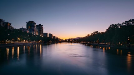 Serene Cityscape at Dusk with Glowing Lights and Calm River Reflection