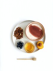 Healthy breakfast with granola, honey, peach and blueberry. On a white plate. A honey stick is next to the plate. White background