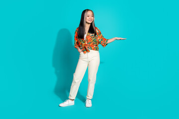 Full length photo of cheerful pretty lady dressed orange shirt showing arm length empty space isolated blue color background