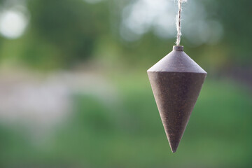 Old plumb bob, plummet or conical iron hanging with rope for measurement level, use for determining perpendicularity . Concept, work tool for construction and carpentry.      