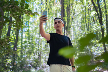 A report on forest trails perfect for running and physical activity. A man with a phone in hand films himself jogging in the woods.