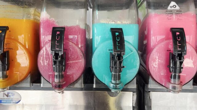 Rainbow-colored slush dispensers.  Cold granita slushy making machines. Smoothie  TRANSLATE: frozen juice, ice cream lemonade.