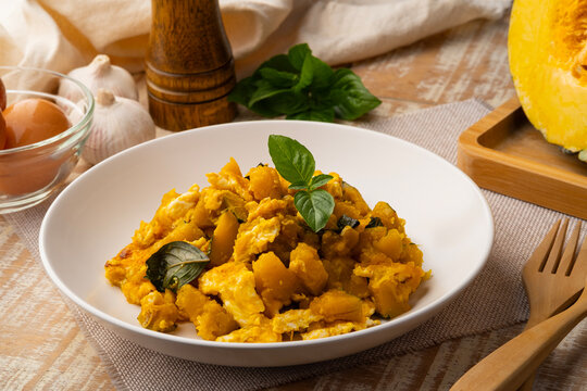 Stir-fried Pumpkin with Eggs and Sweet Basil in white plate (pad fak tong)
