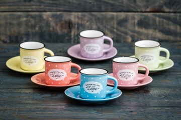 Colorful polka dot coffee cups and saucers arranged on a rustic wooden surface with a vintage charm.