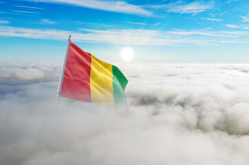 Guinea flag aerial view in beautiful sky with clouds. Top-down drone shot at sunrise or sunset. Aerial bird's eye view of the flag with cloudscape.