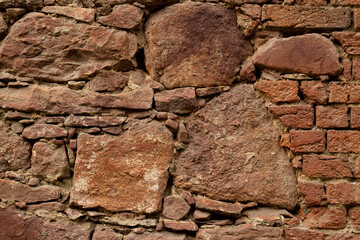 Close up. Old red wall made of various sizes  stone and bricks. Background or texture. 