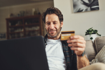 Man, home and smile on laptop with credit card on sofa for online shopping, payment and saving plan. Rewards, happy and couch in living room for internet banking, budget and investment or finance