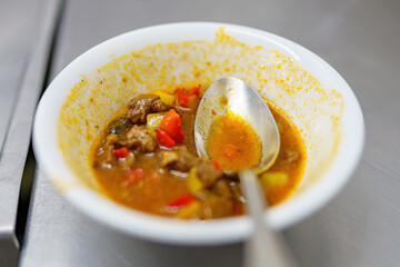 Unfinished soup in a plate with a spoon on the table.