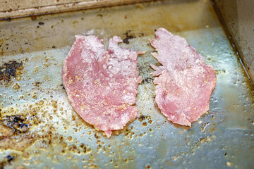 Frying a pork chop on the stove in a restaurant kitchen.